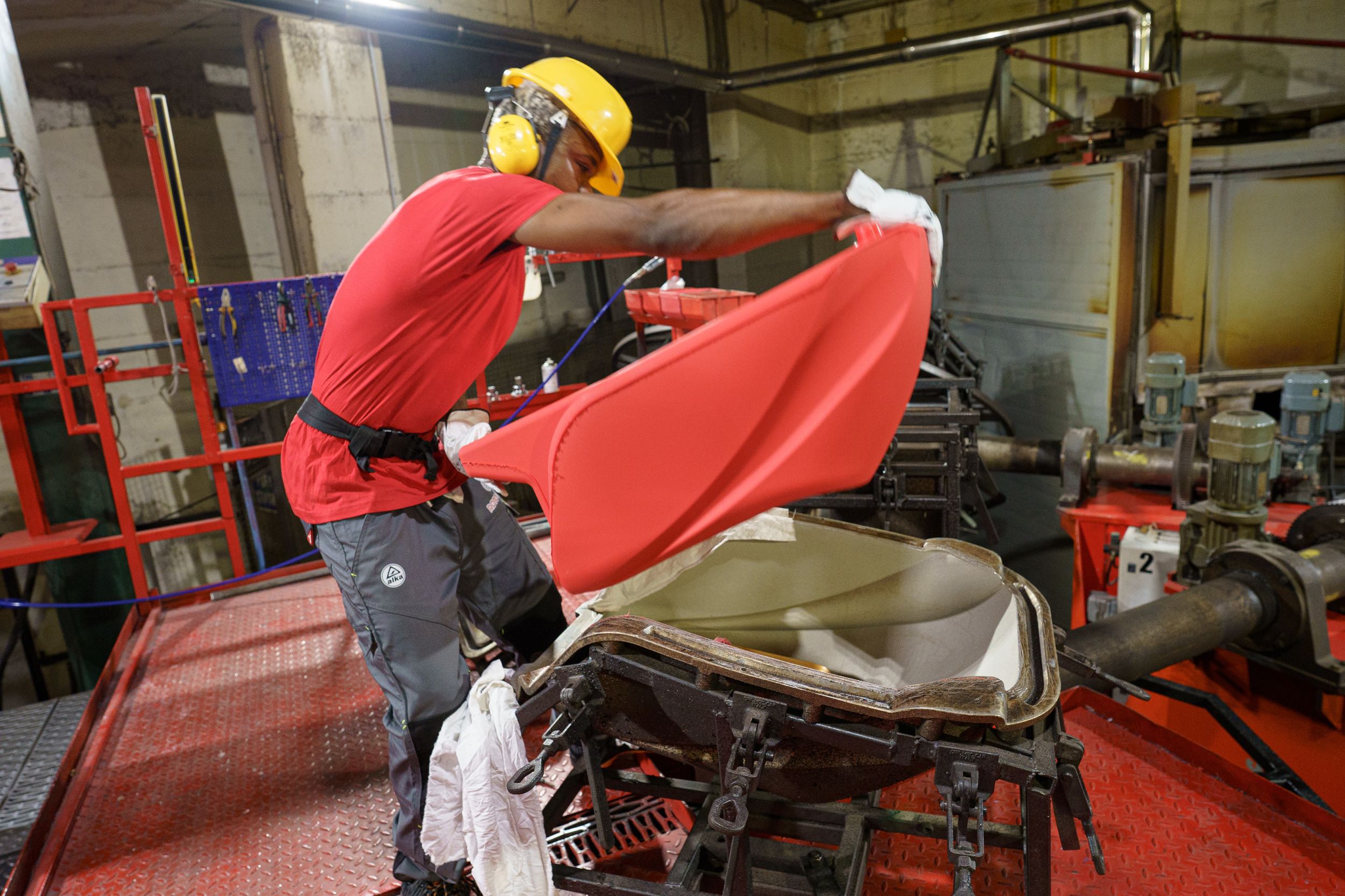 operaio che estrae rotoformato plastico rosso a due mani da stampo